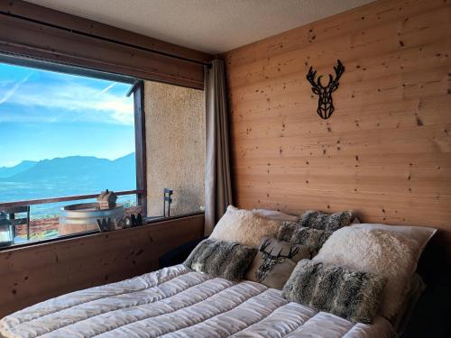 een slaapkamer met een bed en een groot raam bij appartement montagne- le petit Chaillol in Saint-Michel-de-Chaillol