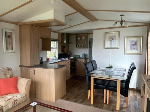 a kitchen and living room with a table and chairs at Lili-anns Retreat Cosy Holiday Home in Millom