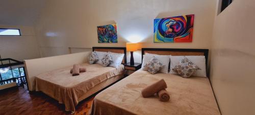 two beds in a room with paintings on the wall at Alta Vista De Boracay by Crystal in Boracay