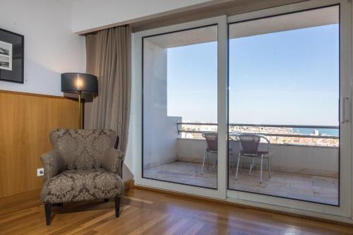 a living room with a chair and a balcony at B&B HOTEL Sado Setúbal in Setúbal