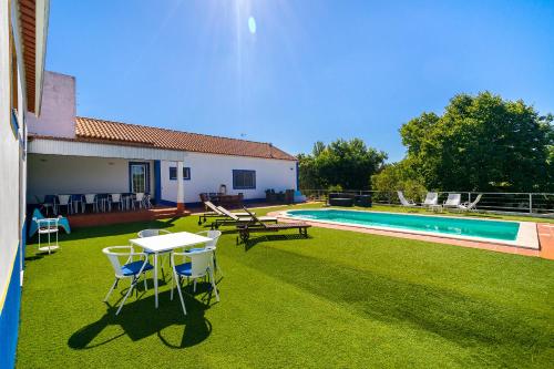 a yard with a table and chairs next to a pool at Chaparral Wonderful house in Nature 1h from Lisbon by Soulplaces in Silveiras