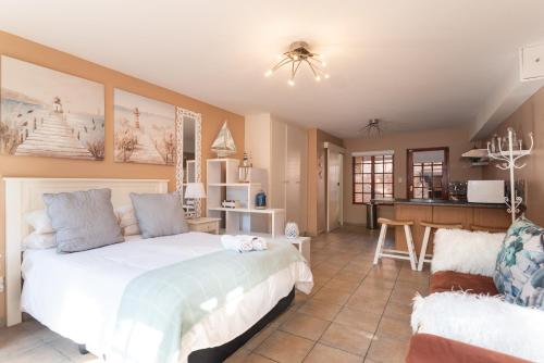 a bedroom with a large white bed and a kitchen at Bougainvillea 1 in KwaDukuza
