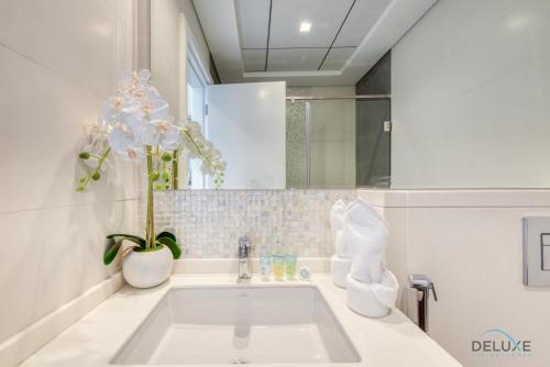 a bathroom with a sink and a vase with flowers at Contemporary 1BR at Prime Views Meydan by Deluxe Holiday Homes in Dubai