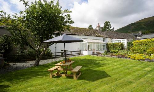 a house with a picnic table and an umbrella at Blease Garth in Threlkeld