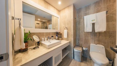 ein Badezimmer mit einem Waschbecken, einem WC und einem Spiegel in der Unterkunft Special Price Deluxe 2BR at El Portillo in Las Terrenas