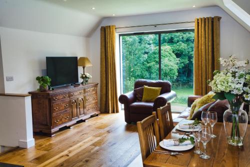 ein Wohnzimmer mit einem Tisch, Stühlen und einem TV in der Unterkunft The Loft at Hewletts Farm - Stunning Apartment on The Cotswold Way Close to Cheltenham in Cheltenham