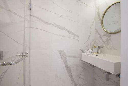 een witte badkamer met een wastafel en een spiegel bij Modern 1BR in Dizengoff by Holiday-rentals in Tel Aviv