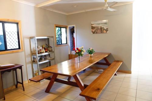 uma sala de jantar com uma mesa de madeira com flores em Happytourcairns sharehouse em Cairns