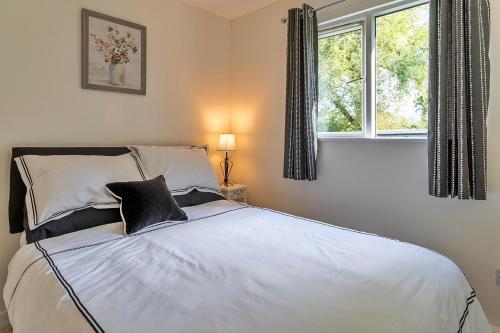 a bedroom with a large white bed with two windows at Finest Retreats - Rosebud Cottage in Wedmore