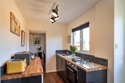 a kitchen with a stove and a counter top at Finest Retreats - Rosebud Cottage in Wedmore