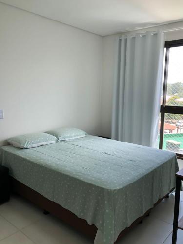 a bed in a white room with a window at Itacolomi Home Club Apto 404 T1 in Penha