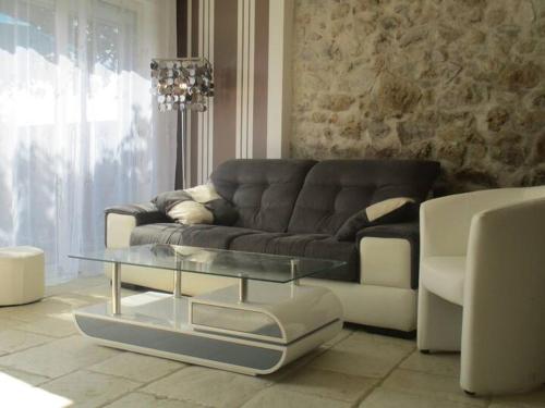 a living room with a couch and a glass coffee table at La p'tite maison du Chateau in Éclassan