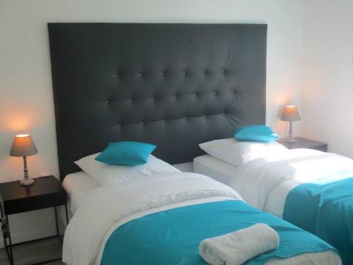 1 dormitorio con 2 camas y almohadas azules en La p'tite maison du Chateau, en Éclassan