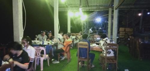 een groep mensen die aan tafel zitten in een restaurant bij Villa Mekong Guesthouse in Pakbeng