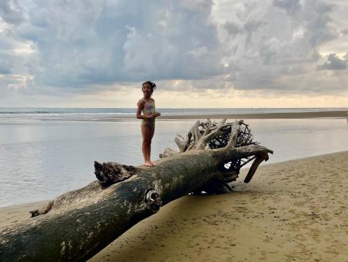 a young girl standing on a log on the beach at Cabinas Chazu #2 in Quepos