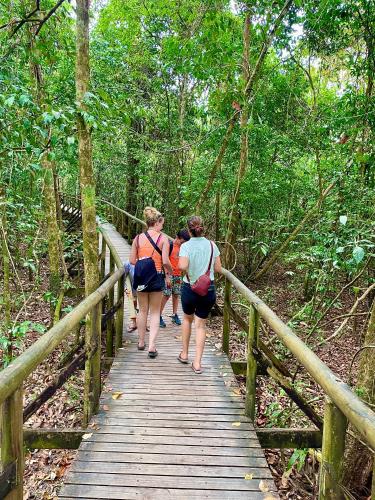 three people walking down a wooden bridge in the forest at Cabinas Chazu #2 in Quepos