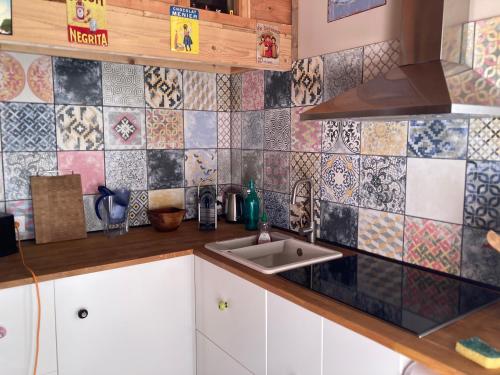 a kitchen with a sink and a tiled wall at LA CABANE Charmante petite maison 2 chambres à 2,5km plage in Saint-Georges-dʼOléron