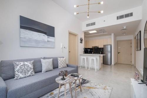 a living room with a gray couch and a kitchen at Restful apartment with private terrace by the pool in Dubai