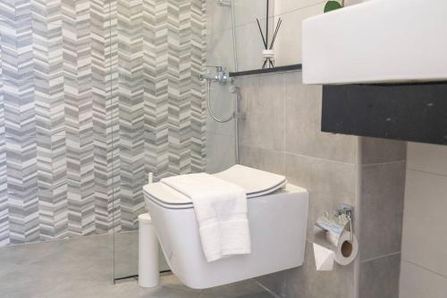 a bathroom with a white toilet and a shower at Restful apartment with private terrace by the pool in Dubai