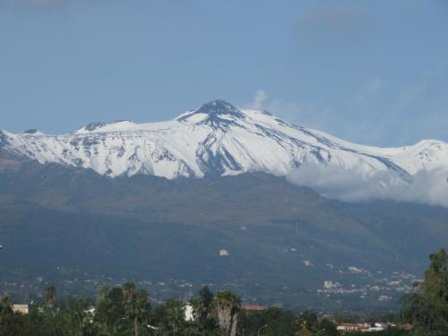 a snow covered mountain in front of a city at Le Case Del Merlo Turismo Rurale in Milo