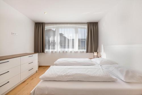 a white bedroom with a bed and a window at Residence Diana Apartment 402 in Terento