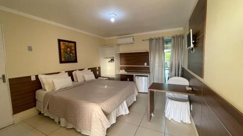 um quarto de hotel com uma cama, uma mesa e uma janela em HOTEL UNA em Palmares