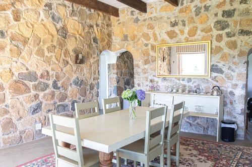 ein Esszimmer mit einem Tisch, Stühlen und einer Steinmauer in der Unterkunft Dragons Landing Guest Farm in Underberg