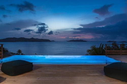 a blue swimming pool with a view of the ocean at Infiniti 2 BR Private Luxury Villa Breath Taking View in St Barth in Pointe Milou