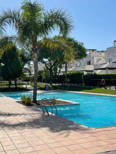 - une piscine avec un palmier et un banc dans l'établissement El Condado de Alhama Golf Resort Naranjos 7 house 589, à Alhama de Murcia