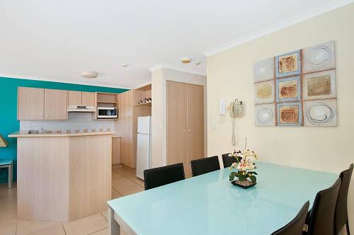 cocina y comedor con mesa y sillas en Blue Waters Apartments, en Gold Coast