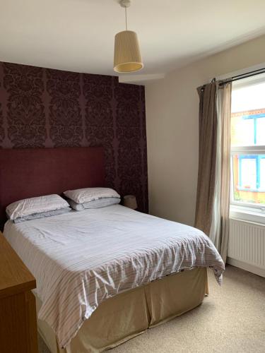 een slaapkamer met een bed met een rood hoofdeinde en een raam bij Liverpool in Woolton