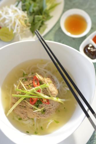 a bowl of chicken noodle soup with chopsticks on a table at Banyan Tree Lang Co in Lang Co