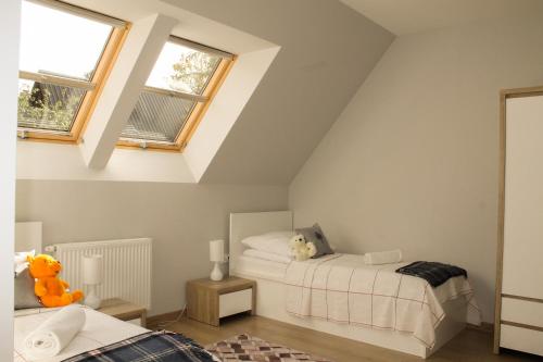 two beds in a attic bedroom with two windows at Zakopane Domki Wisienka in Zakopane