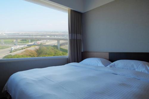 a bedroom with a bed and a large window at City Suites - Taoyuan Gateway in Dayuan