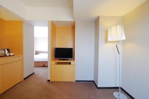 a hotel room with a television and a bedroom at City Suites - Taoyuan Gateway in Dayuan