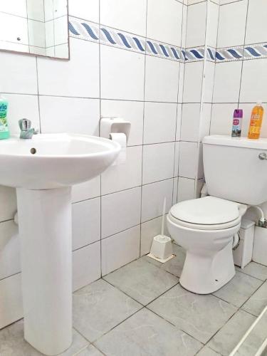 ein Badezimmer mit einem weißen WC und einem Waschbecken in der Unterkunft Truthvacay in Mombasa