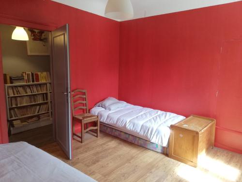 1 dormitorio con una pared roja, 1 cama y 1 silla en Le Grand Feuvrier en Dole