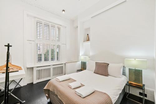 ロンドンにある1 & 2 Bed Cosy Apartments next to Earls Court FREE WIFIの白いベッドルーム(ベッド1台、デスク付)