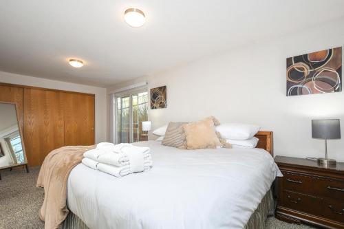 Un dormitorio con una cama blanca con toallas. en Cozy Couve Apartment Close To Everything!, en Vancouver