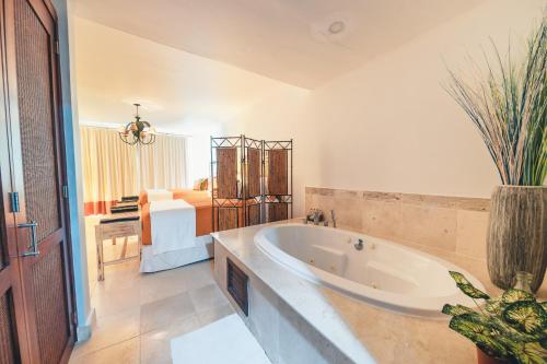 a large bathroom with a tub and a bedroom at Punta Palmera Beachfront Apartment in Punta Cana