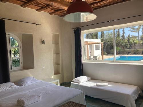 - 2 lits dans une chambre avec une fenêtre et une piscine dans l'établissement The House just 8 km from Essaouira and its beaches, à Ida Ougourd