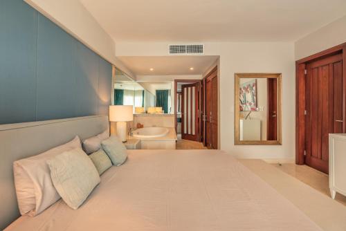 a bedroom with a large bed with a bathroom at NEW 2BR Apt w Jacuzzi Punta Palmera CBA in Punta Cana