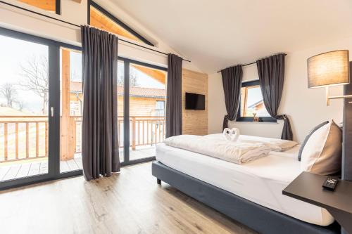Schlafzimmer mit einem Bett und großen Fenstern in der Unterkunft Inzell Chalets by ALPS RESORTS in Inzell
