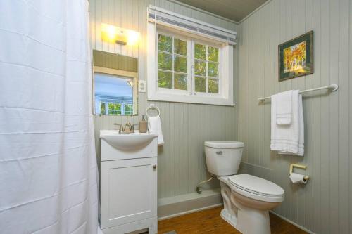 a bathroom with a toilet and a sink and a window at Adorable Cottage Among Trees Close To Everything in Vancouver