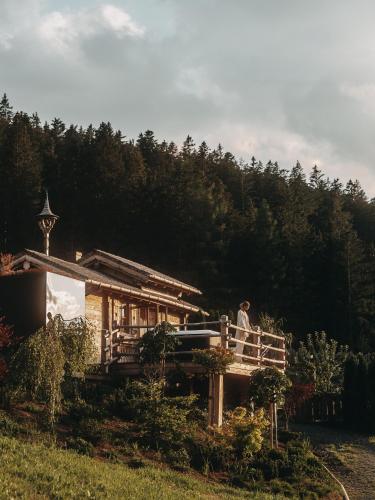 a man sitting on a porch of a house at Jufenalm BOHO & Wellnesshotel in Maria Alm am Steinernen Meer