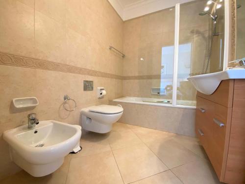 een badkamer met een toilet, een wastafel en een bad bij Apartamento Boavista in Lagos