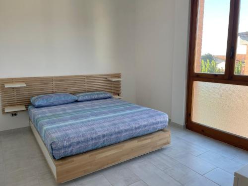 a bedroom with a bed with a wooden headboard and a window at Lara's Apartment in Lido di Camaiore