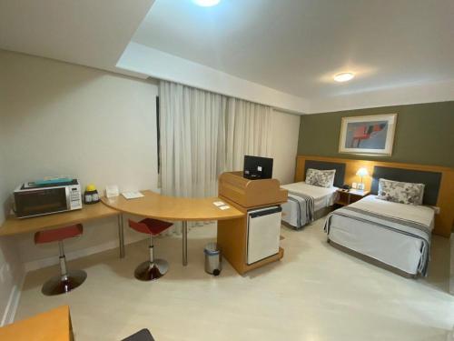 a room with two beds and a table with a desk at Bienal First Class Flat Service - UH607 in São Paulo