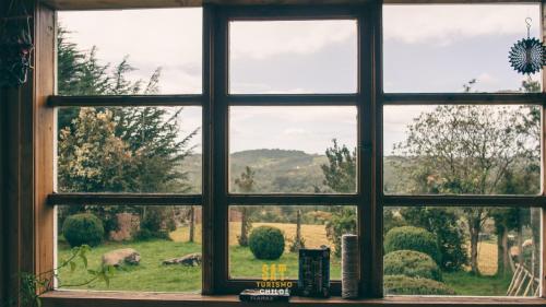 a window with a view of a field of grass at Casa Pindal in Puqueldón