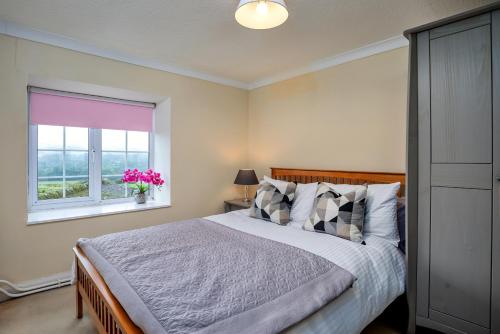 een slaapkamer met een bed en een raam met roze bloemen bij Finest Retreats - Cloggers Cottage in Darley